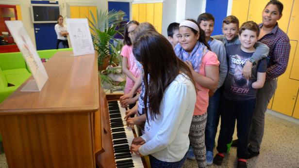 Eine Gruppe von Kindern spielt gemeinsam auf einem Klavier in einem Klassenzimmer.
