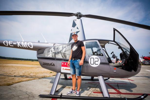 Thomas Morgenstern posiert vor einem Hubschrauber mit seinem Konterfei.