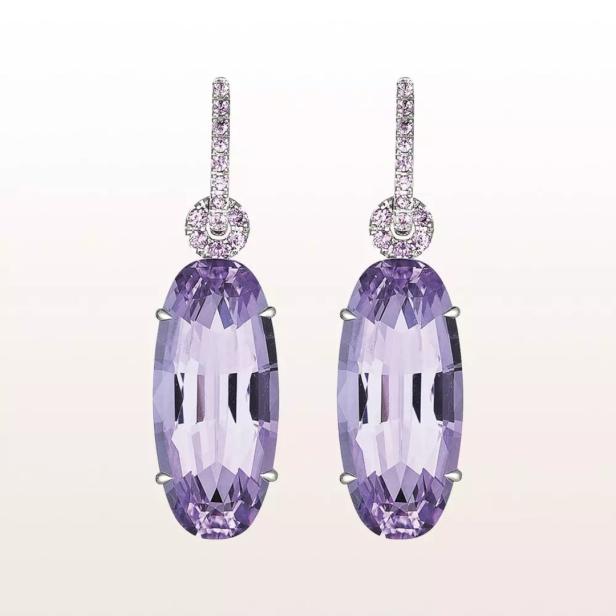 Nahaufnahme von zwei lila Ohrringen mit Diamanten.