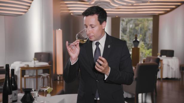 Ein Sommelier in einem Restaurant, der an einem Glas Weißwein riecht.