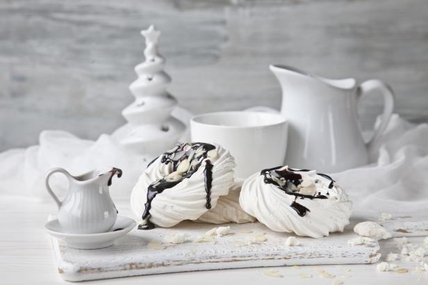 Merengue with chocolate sauce and a mug of milk on a white wooden background.Christmas concept. Selective focus, shallow depth of field, close-up