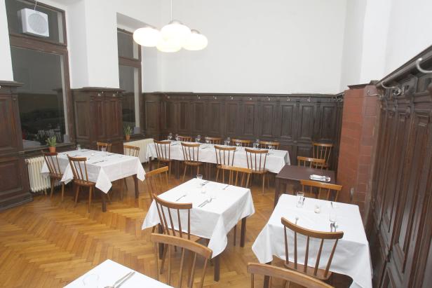 Ein Speisesaal mit gedeckten Tischen und Holzvertäfelung.