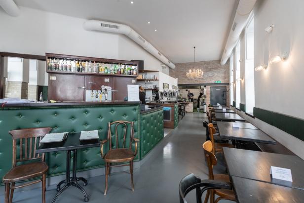 Innenansicht eines leeren Restaurants mit Bar und Tischen.