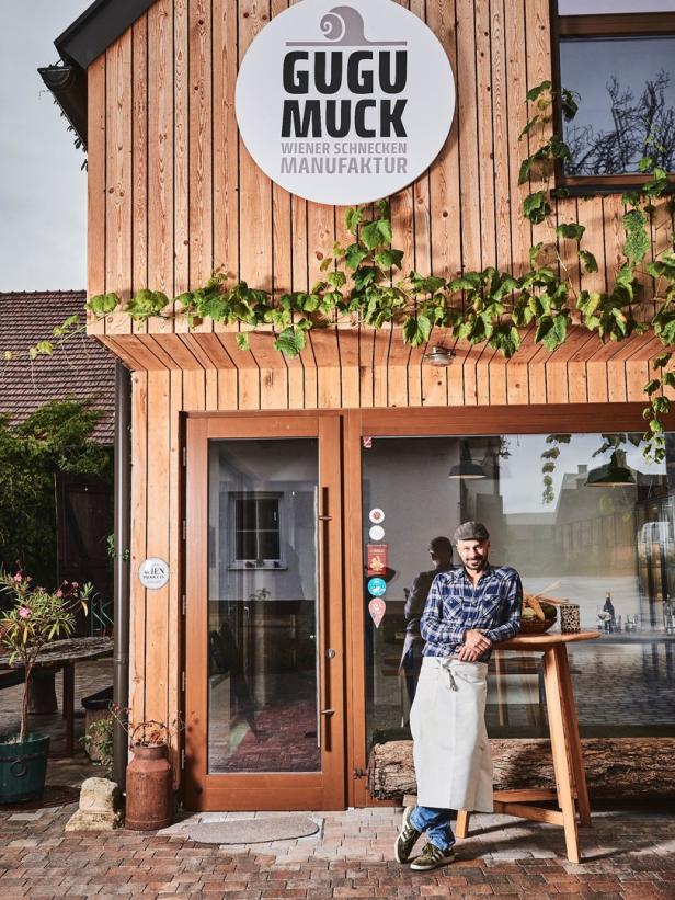 Ein Mann mit Schürze steht vor dem Eingang der „Gugu Muck Wiener Schnecken Manufaktur“.