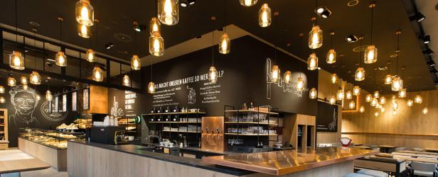 Innenansicht eines Cafés mit vielen Glühbirnen in Einmachgläsern über der Theke.