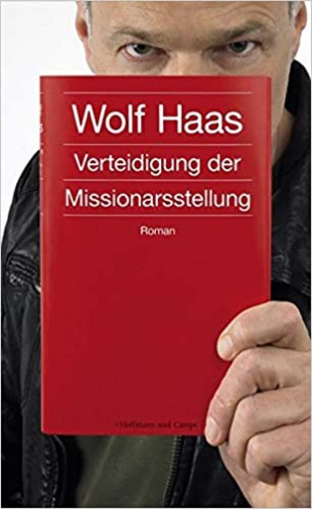 Ein Mann hält das Buch „Verteidigung der Missionarsstellung“ von Wolf Haas vor sein Gesicht.