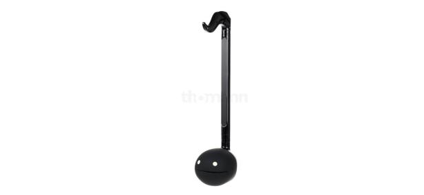 Ein schwarzes Otamatone-Synthesizer-Spielzeug vor einem weißen Hintergrund.