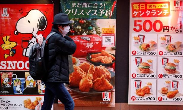 Eine Person geht an Werbeplakaten von KFC und Snoopy in Japan vorbei.