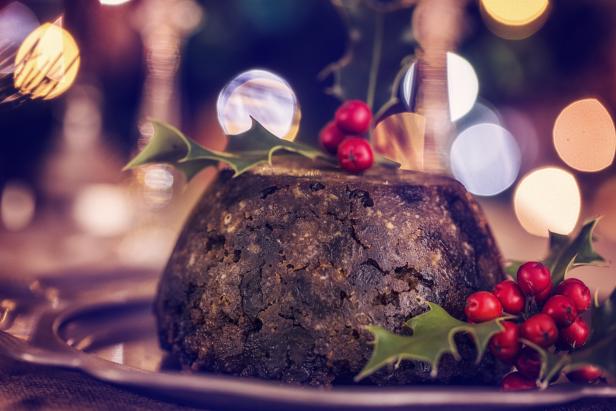 Ein Weihnachtspudding ist mit Stechpalmenzweigen und roten Beeren dekoriert.