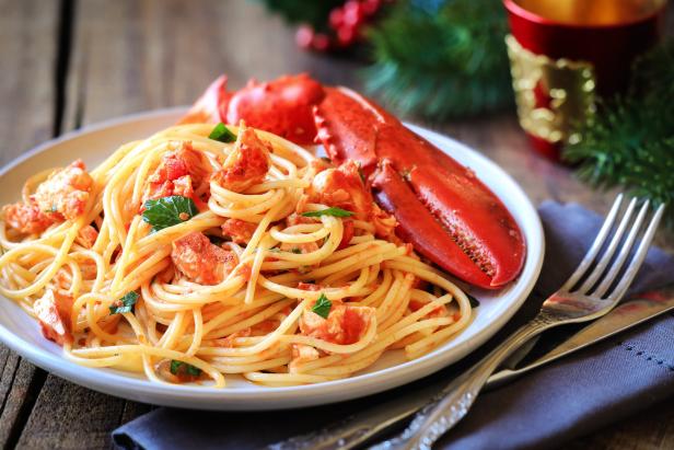 Ein Teller Spaghetti mit Hummersauce und einer Hummerschere liegt auf einem Tisch.