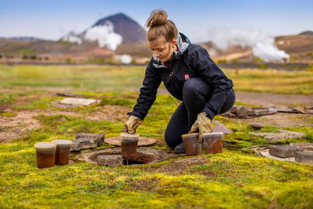 Eine Frau nimmt Bodenproben in einer geothermalen Region Islands.