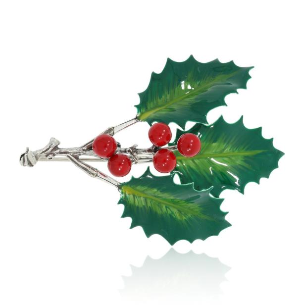 Eine Brosche in Form eines Stechpalmenzweigs mit roten Beeren und grünen Blättern.