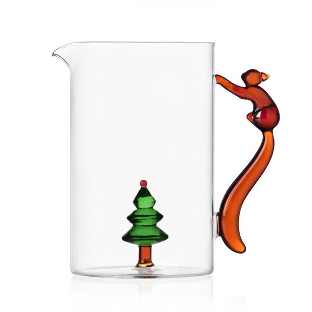 Ein Glasbehälter mit einem kleinen Weihnachtsbaum darin und einem Griff in Form einer Figur.