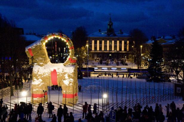 Ein großer, strohgedeckter Julbock steht auf einem verschneiten Platz in Gävle, Schweden.