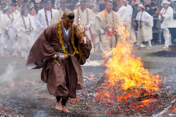 Ein barfüßiger japanischer Mönch schreitet über ein Feuer.