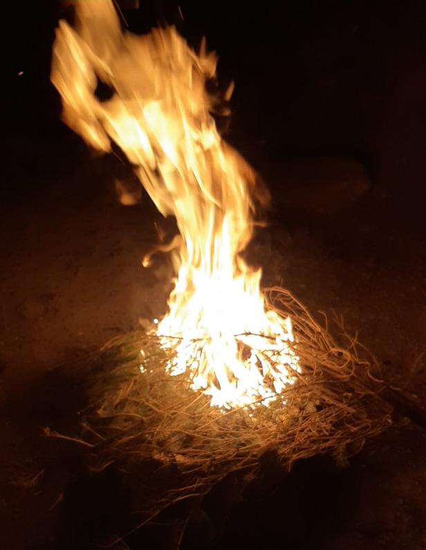 Ein kleines Lagerfeuer brennt im Dunkeln.