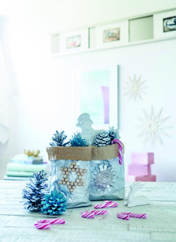 Weihnachtliche Dekoration mit bemalten Tannenzapfen und Zuckerstangen auf einem Tisch.