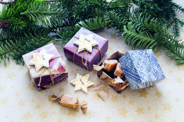 Weihnachtliche Szene mit Geschenken, Süßigkeiten und Tannenzweigen.