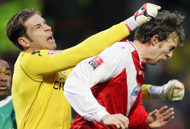 Ein Torwart greift einem anderen Fußballspieler ins Haar.