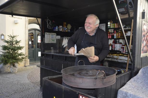 Ein Mann verkauft Maroni an einem Stand auf dem Marktplatz.