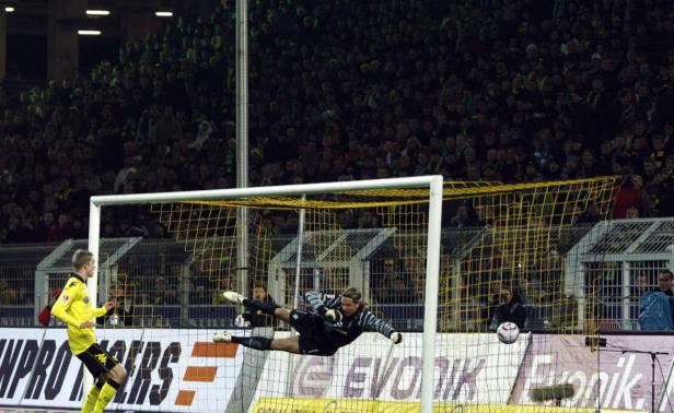 Ein Torwart hechtet nach dem Ball vor einer Zuschauermenge.