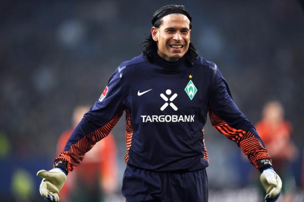 Ein lächelnder Fußballtorwart in seinem Trikot von Werder Bremen.