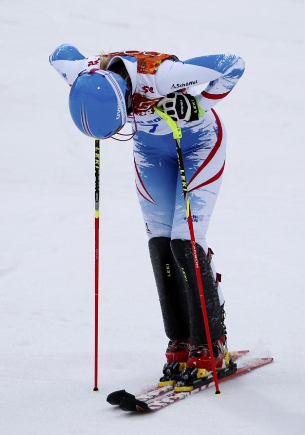 Eine Skirennläuferin beugt sich erschöpft nach einem Rennen nach vorne.