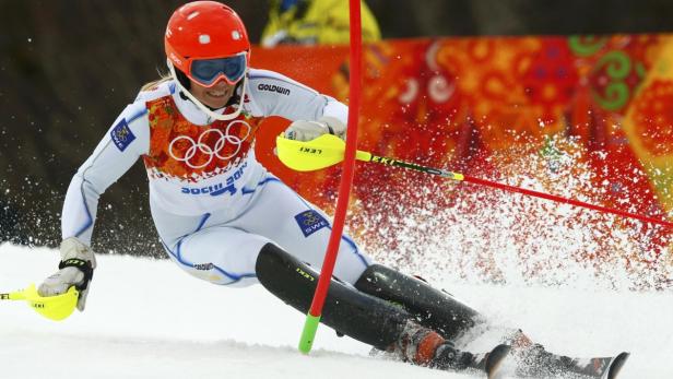 Eine Skirennläuferin im weißen Anzug fährt einen Slalomkurs herunter.