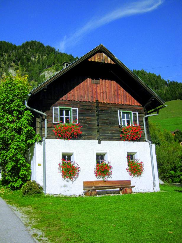 Ein traditionelles Holzhaus mit blühenden Blumenkästen unter den Fenstern.