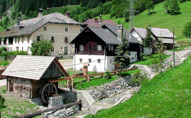 Eine malerische Wassermühle in einer ländlichen Gegend mit traditionellen Häusern.