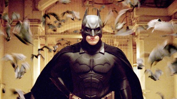 Batman steht inmitten einer Schar von Fledermäusen.