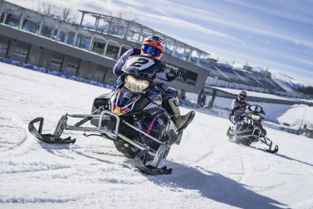 Zwei Motocross-Fahrer auf Schneemobilen fahren auf einer schneebedeckten Piste.
