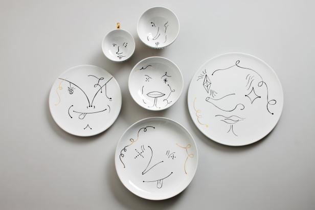 Teller, Schalen und eine Tasse sind mit skizzenhaften Gesichtern verziert.