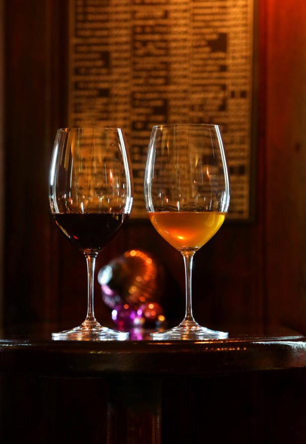 Zwei Gläser, eines mit Rotwein und eines mit Weißwein, stehen auf einem Tisch.