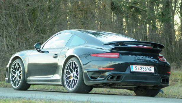 Ein schwarzer Porsche 911 Turbo S steht auf einer Straße.