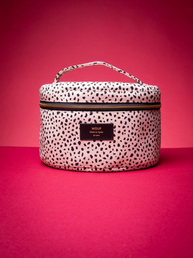 Eine Kosmetiktasche mit Dalmatiner-Muster der Marke Wouf vor einem roten Hintergrund.