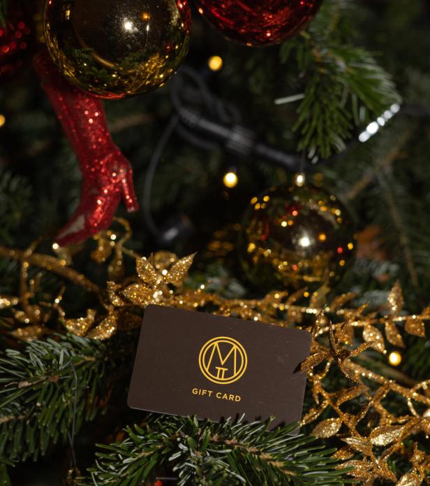 Eine Geschenkkarte liegt auf einem geschmückten Weihnachtsbaum.