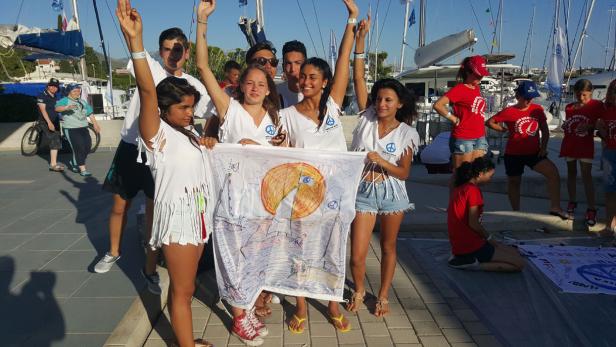 Eine Gruppe junger Leute hält ein Friedensbanner in einem Hafen.