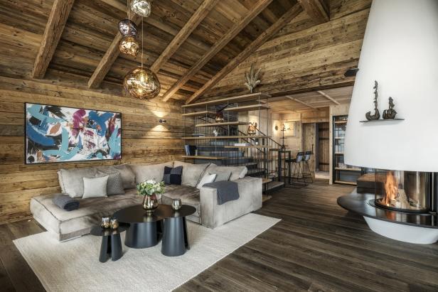 Ein Wohnzimmer mit Holzwänden, einem Sofa, einem Kamin und einer Treppe.
