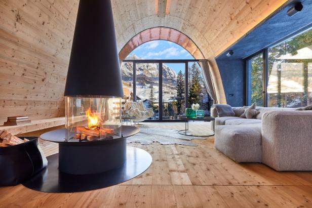 Ein Wohnzimmer mit Kamin und Blick auf eine verschneite Berglandschaft.