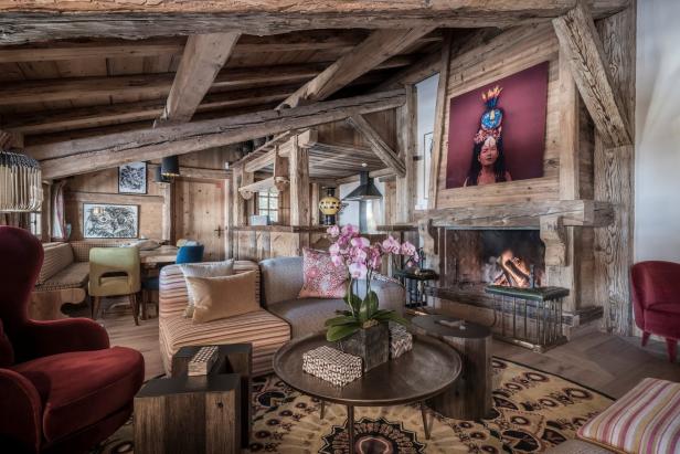 Ein Wohnzimmer im Chalet-Stil mit Holzbalken, Kamin und farbenfrohen Akzenten.