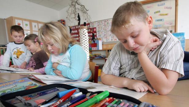 Eine Gruppe von Grundschulkindern sitzt an einem Tisch und liest Bücher.