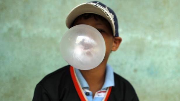 Ein Junge bläst eine große Kaugummiblase.