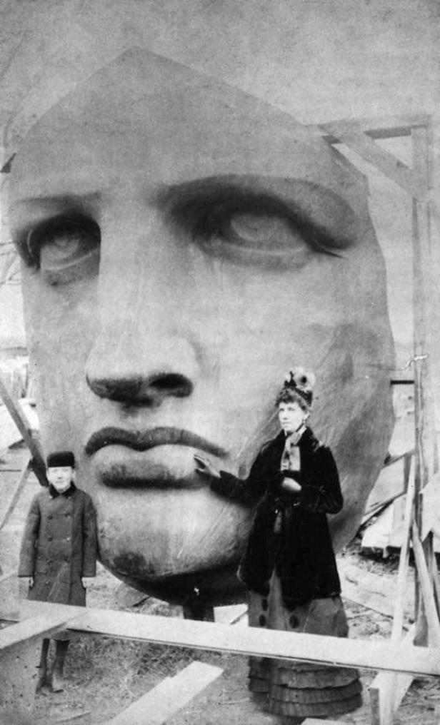 Ein historisches Foto zeigt den Kopf der Freiheitsstatue mit zwei Personen davor.