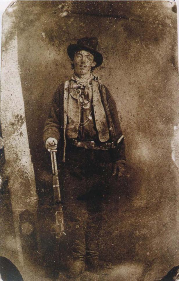 Ein Porträt von Billy the Kid mit Hut und Gewehr.