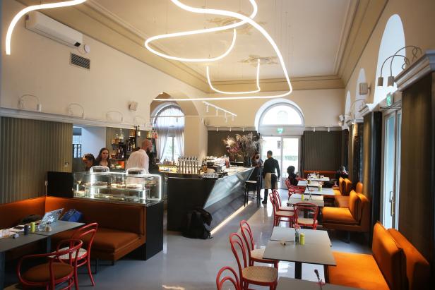 Innenansicht eines Cafés mit Gästen und Personal hinter der Theke.