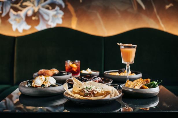 Eine Auswahl an Speisen und Getränken, darunter ein Tamale, Cocktails und Maiskolben.