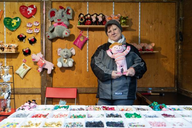 Eine Frau steht an einem Stand mit Stofftieren und kleinen Glücksbringern.