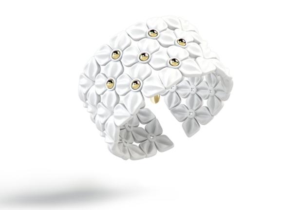 Ein weißes Armband mit Blumenmuster und goldenen Akzenten.