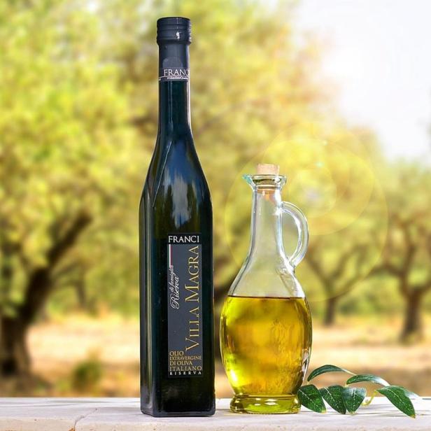 Eine Flasche „Villa Magra“ Olivenöl und ein Glasbehälter mit Olivenöl stehen auf einem Tisch.